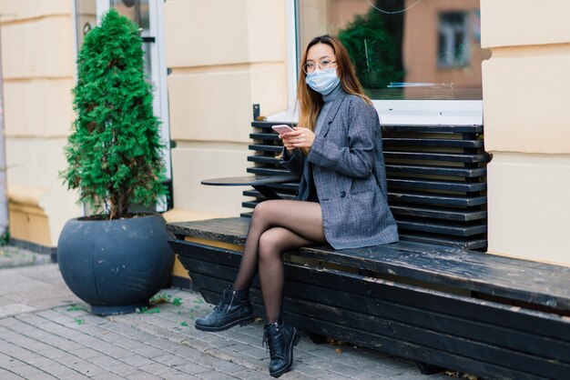 Junge fsian frau mit gesichtsmaske steht an einer inländischen straße. Konzept der neuen Normalität der Pendler nach der Covid-19-Epidemie