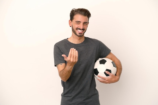 Junge Fußballspielerfrau isoliert auf weißem Hintergrund, die einlädt, mit der Hand zu kommen Glücklich, dass Sie gekommen sind