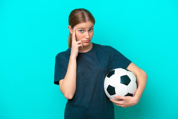 Junge Fußballspielerfrau lokalisiert auf blauem Hintergrund, der eine Idee denkt