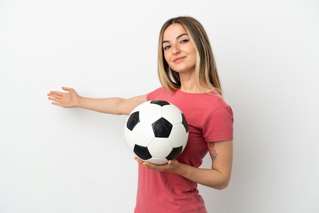 Junge Fußballspielerfrau über isolierter weißer Wand, die die Hände zur Seite ausstreckt, um zum Kommen einzuladen?