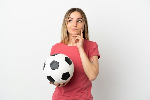 Junge Fußballspielerfrau über isolierter weißer Wand, die Zweifel hat und denkt