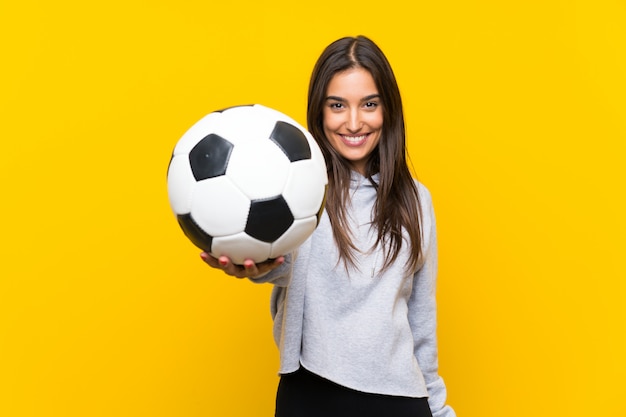 Junge Fußballspielerfrau über lokalisierter gelber Wand