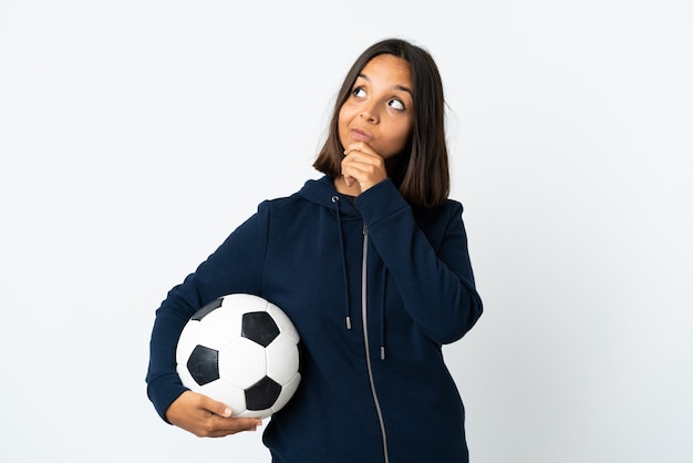 Junge Fußballspielerin auf Weiß, die Zweifel beim Aufblicken hat