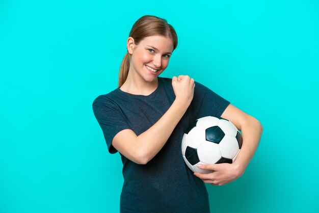 Junge Fußballspielerin lokalisiert auf blauem Hintergrund, der einen Sieg feiert