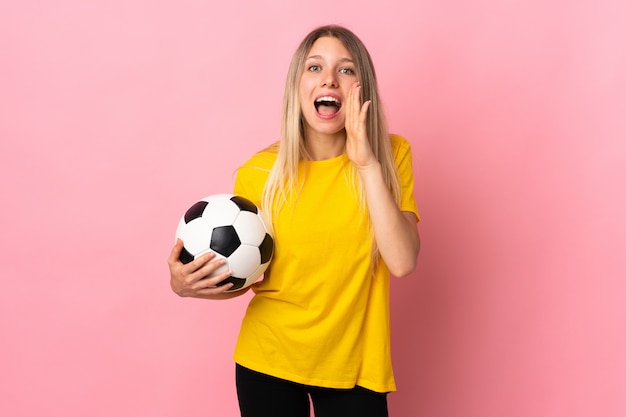 Junge Fußballspielerin lokalisiert auf rosa Wand, die mit Mund weit offen schreit