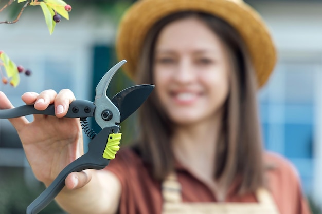 Junge Gärtnerin mit Gartenschere in der Hand vor Gartenhaus