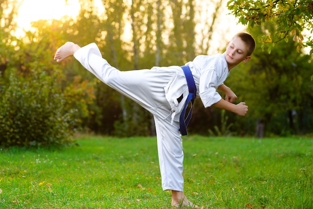 Junge gekleidete Kimono, der Karateübungen im Freien macht