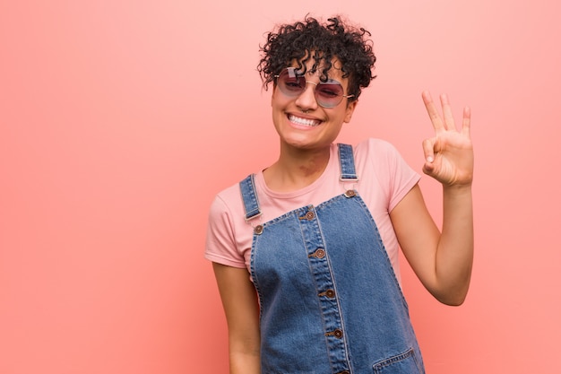 Junge gemischte Afroamerikanerjugendlichfrau zwinkert einem Auge und hält eine okaygeste mit der Hand.