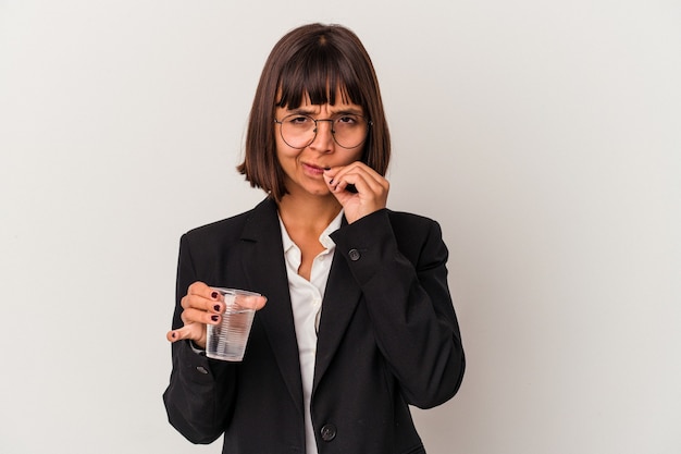Junge gemischte Geschäftsfrau, die ein Glas Wasser lokalisiert auf weißem Hintergrund mit den Fingern auf den Lippen hält, die ein Geheimnis halten.