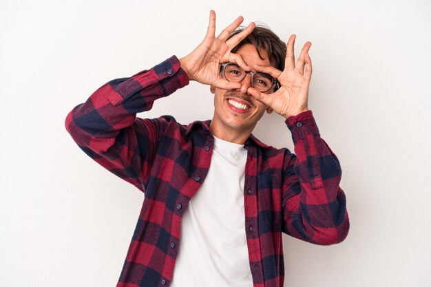 Junge gemischte Rasse Mann isoliert auf weißem Hintergrund zeigt ein OK-Zeichen über den Augen