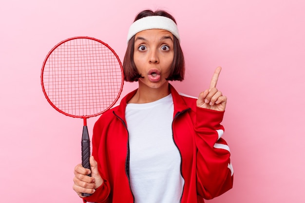 Junge gemischte Rassenfrau, die Badminton spielt, isoliert auf rosa Hintergrund, der einige große Idee, Konzept der Kreativität hat.