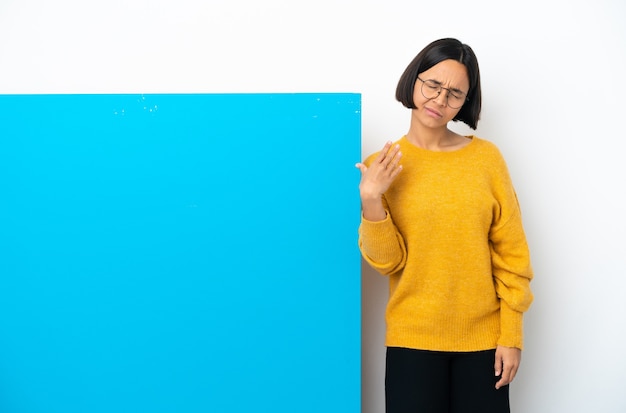 Junge gemischte Rassenfrau mit einem großen blauen Plakat lokalisiert auf weißem Hintergrund mit müde und krankem Ausdruck