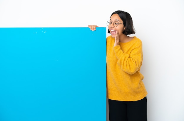 Junge gemischtrassige Frau mit einem großen blauen Plakat isoliert auf weißem Hintergrund schreien mit weit geöffnetem Mund zur Seite