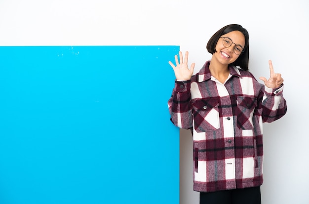 Junge gemischtrassige Frau mit einem großen blauen Plakat isoliert auf weißem Hintergrund und zählt sieben mit den Fingern