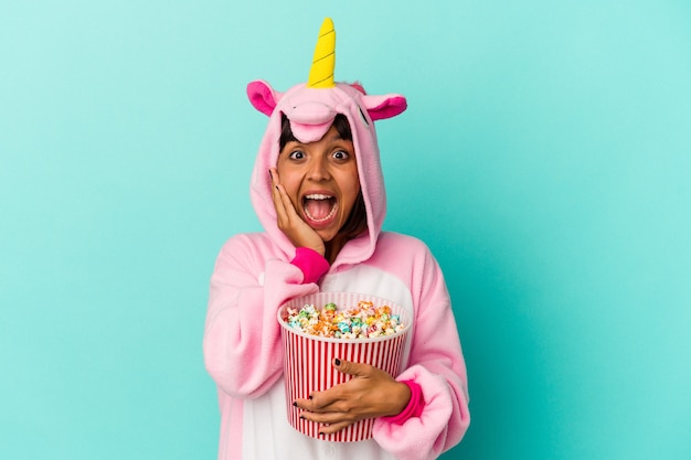 Junge gemischtrassige Frau trägt einen Einhorn-Pyjama und isst Popcorn
