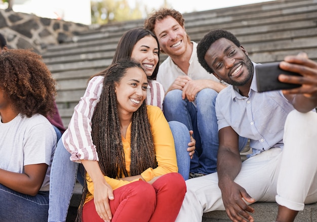 Junge gemischtrassige Freunde, die ein Selfie mit Smartphone im Freien machen - Millennial-Menschen zusammen in der Stadt