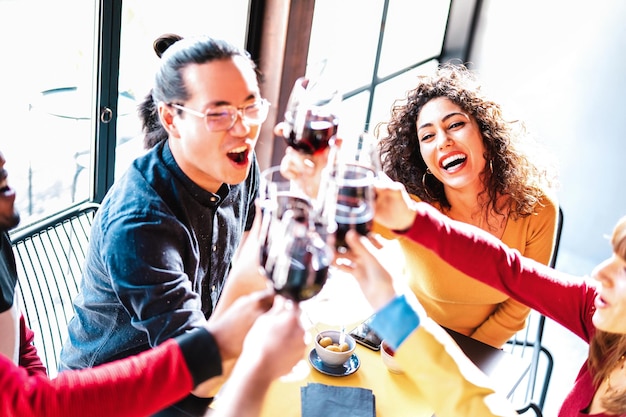 Junge gemischtrassige Freunde trinken und toasten Rotwein bei der Dinnerparty