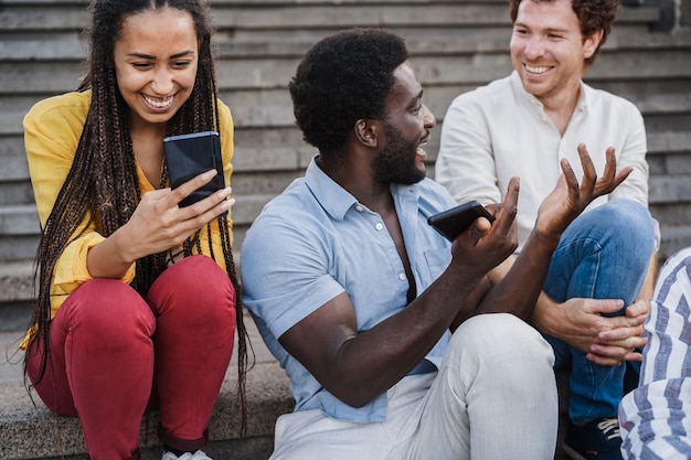 Junge gemischtrassige Menschen, die Mobiltelefone im Freien in der Stadt benutzen - Konzentrieren Sie sich auf das Gesicht eines afrikanischen Mädchens