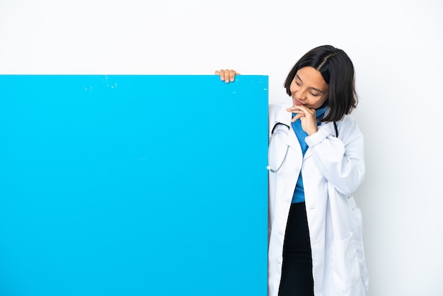 Junge gemischtrassige Ärztin mit einem großen Plakat isoliert auf weißem Hintergrund und nach oben schauend