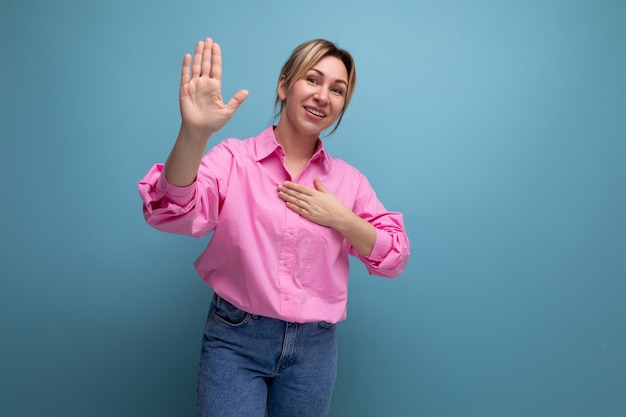 Junge, gepflegte, hübsche europäische blonde Sekretärin in einem rosa Hemd zeigt ihre Hand