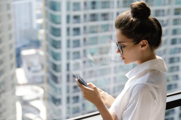 Junge Geschäftsfrau benutzt ein Smartphone in ihrem Büro