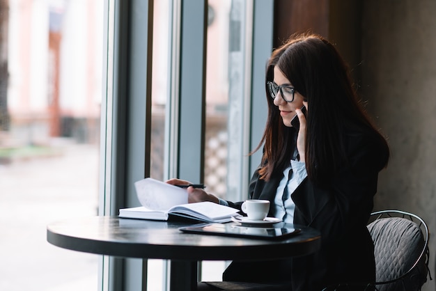 Junge Geschäftsfrau, die am Telefon im Kaffeegeschäft spricht