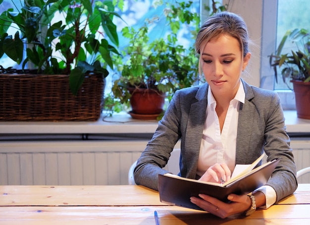 Junge Geschäftsfrau, die am Tisch im Café sitzt und Buch liest Geschäftskonzept