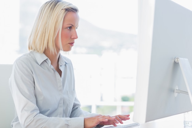 Junge Geschäftsfrau, die an Computer an ihrem Schreibtisch im Büro arbeitet