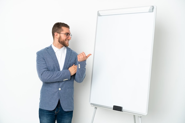 Junge Geschäftsfrau, die eine Präsentation auf weißer Tafel lokalisiert auf weißem Hintergrund zeigt, der zur Seite zeigt, um ein Produkt zu präsentieren