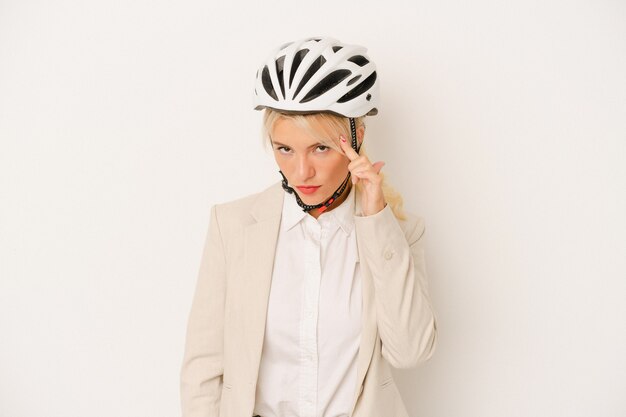 Junge Geschäftsfrau, die Fahrradhelm lokalisiert auf weißem Hintergrund hält, der Tempel mit dem Finger zeigt, denkt, konzentrierte sich auf eine Aufgabe.