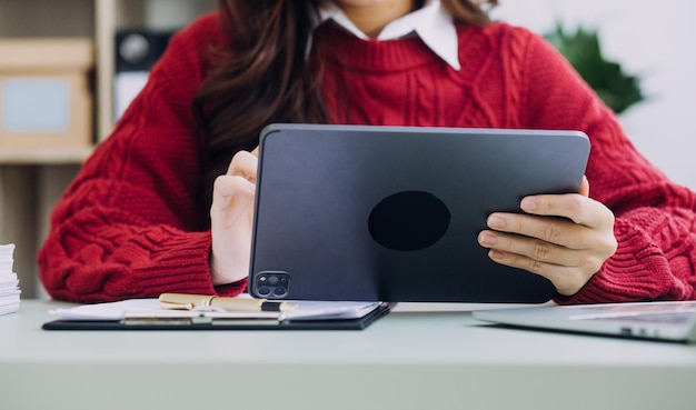 Junge Geschäftsfrau, die im Büro am Tisch sitzt und Smartphone verwendet Auf dem Schreibtisch ist Laptop und Tablet-Computer auf dem Bildschirm Diagramme und Grafiken Frau analysiert Daten Student lernt online