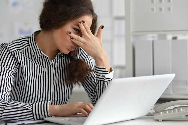 Junge Geschäftsfrau, die im Büro arbeitet, mit Laptop