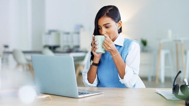 Junge Geschäftsfrau, die nach einer abgeschlossenen Aufgabe eine Kaffeepause macht oder eine Frist einhält, während sie an einem Laptop bei der Arbeit arbeitet Erfreuter weiblicher Unternehmensfachmann, der sich nach dem Senden einer E-Mail ausruht
