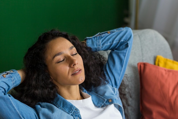 Junge Geschäftsfrau, freiberufliche hispanische Frau, die zu Hause auf dem Sofa ruht, nachdem sie ihre Hände nach der Arbeit geworfen hat