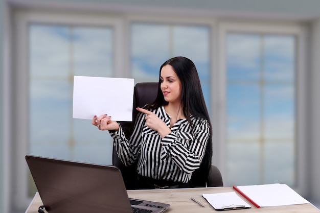 Junge Geschäftsfrau im Büro, die leere Zwischenablage hält