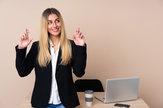 Junge Geschäftsfrau in einem Büro mit den Fingern kreuzend