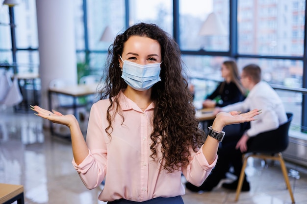 Junge Geschäftsfrau in einer Maske, die während der Coronavirus-Pandemie im Büro arbeitet.