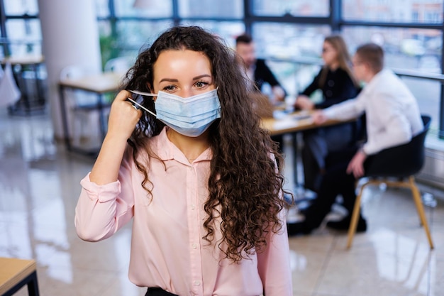 Junge Geschäftsfrau in einer Maske, die während der Coronavirus-Pandemie im Büro arbeitet