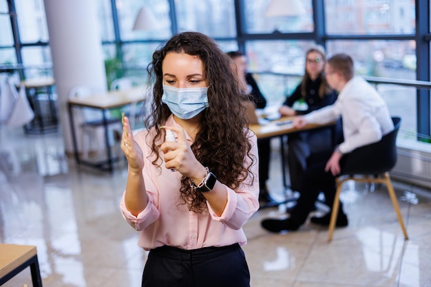 Junge Geschäftsfrau in einer Maske, die während der Coronavirus-Pandemie im Büro arbeitet