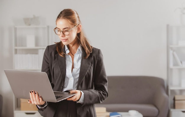 Junge Geschäftsfrau mit Brille, die am Laptop mit zu viel Arbeit im Büro arbeitet Sekretärin