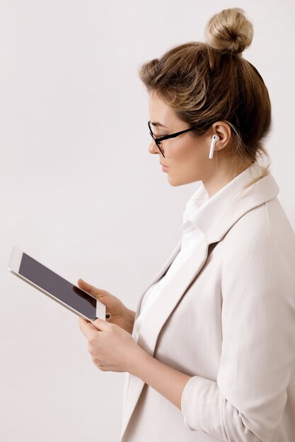 Junge Geschäftsfrau mit einem Tablet-PC auf Grau