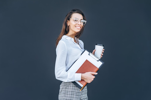 Junge Geschäftsfrau mit Kaffee und Notizbuch auf grauem Hintergrund