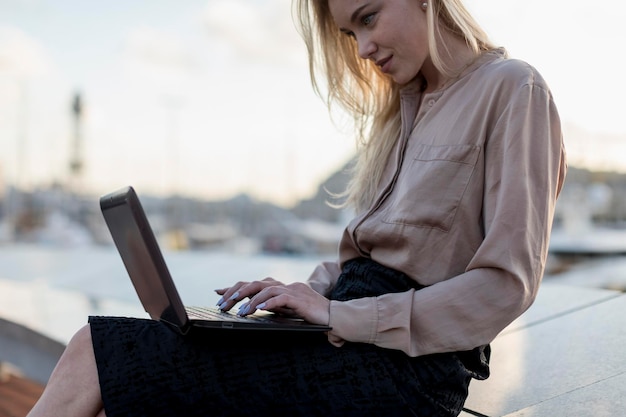 Junge Geschäftsfrau mit Laptop am Wasser