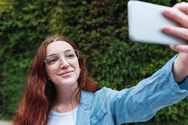 Foto junge geschäftsfrau mit roten haaren macht ein selfie