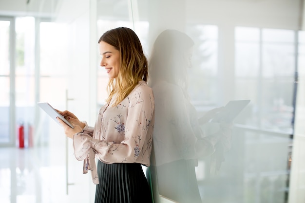 Junge Geschäftsfrau mit Tablette im modernen Büro