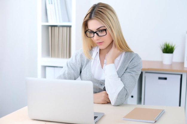 Junge Geschäftsfrau oder Studentin sitzt am Büroarbeitsplatz mit Laptop-Computer. Home-Business-Konzept.