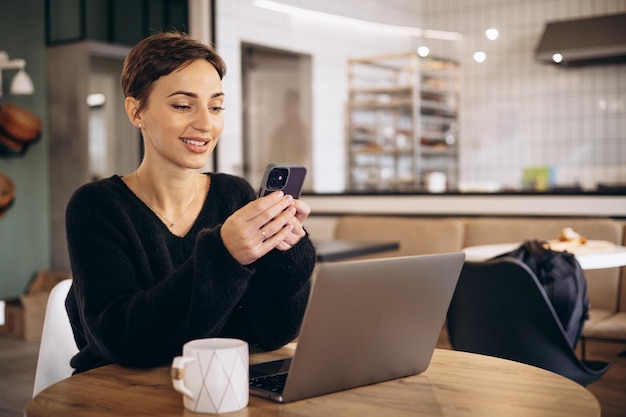 Junge Geschäftsfrau trinkt Kaffee und arbeitet am Laptop in einem Café