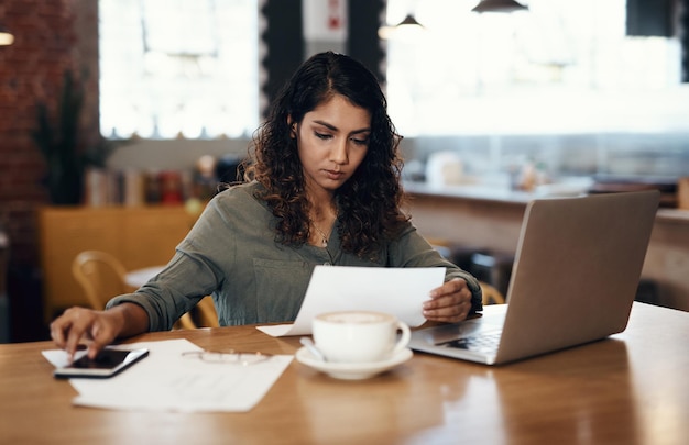 Junge Geschäftsfrau, Unternehmerin und Cafébesitzerin, die überwältigt aussieht, wenn sie Papierkram durchläuft Ernsthafte und besorgte Café-Managerin, die das Logistikblatt für den Monat durchläuft oder liest