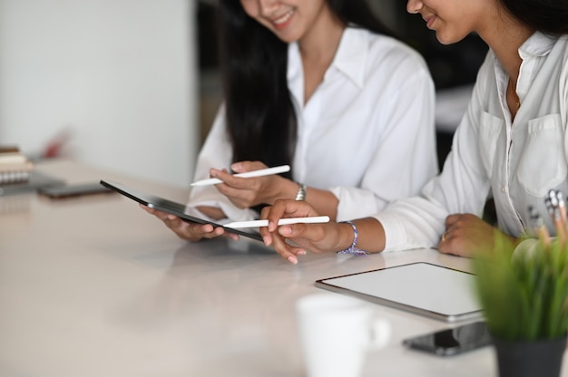 Junge Geschäftsfrauen arbeiten ihre Geschäftsstrategie zusammen mit digitalem Tablet im modernen Büro.