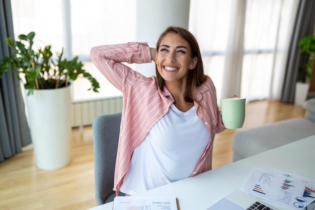 Junge Geschäftsfrauen im Büro trinken Kaffee und schauen durch ein Fenster